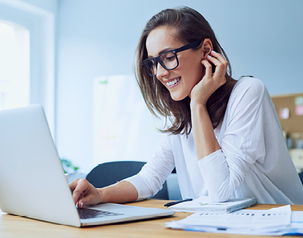 woman with glasses working on a laptop